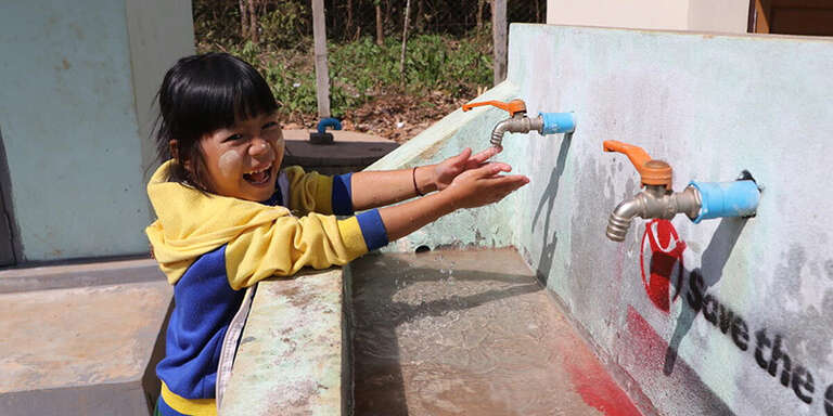 Little girl washing her hands at a Save the Children water station