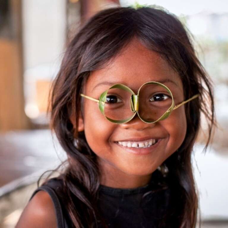 Little girl in Cambodia playing with glasses made out of leaves