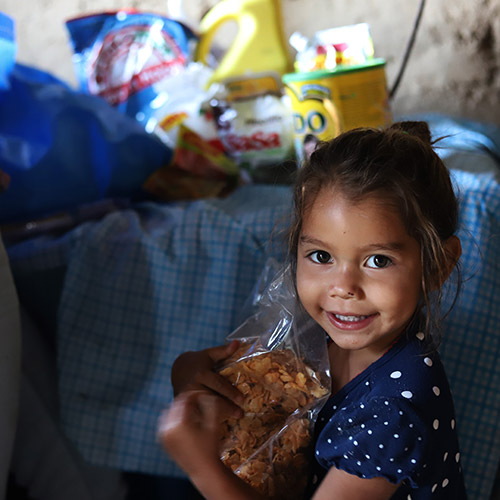 Save the Children - Aleska, 2, holding food her mother bought with a cash voucher. 