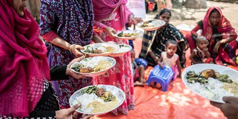 A close up of a group of women holding plates of food. 