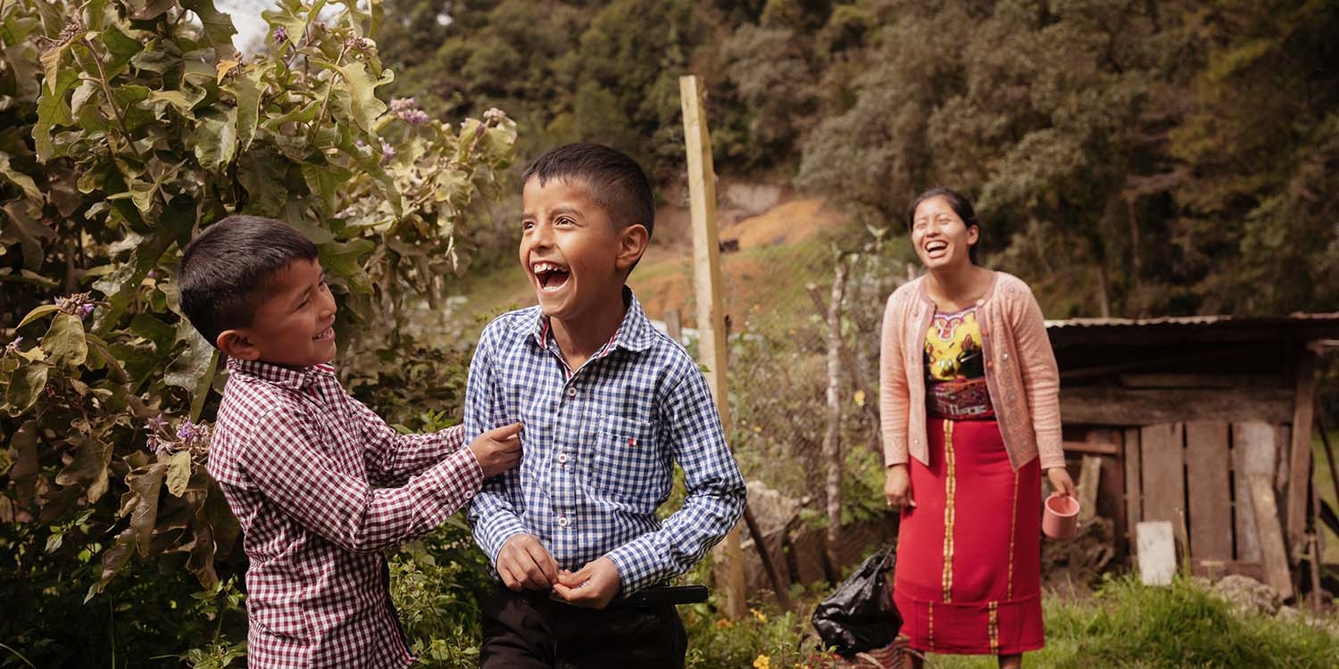 Guatemala, a mother and her two sons laugh together on their farm