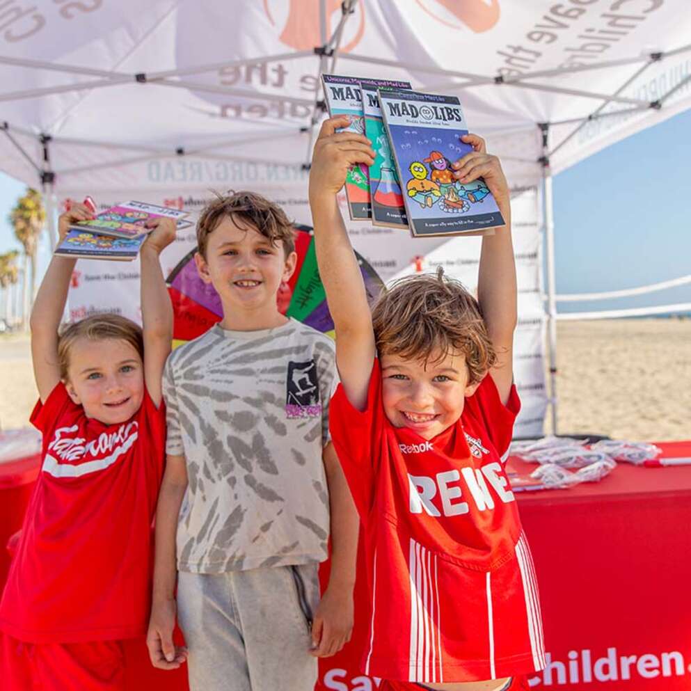 Kids show off Mad Lib books they received during the launch event for Save the Children’s annual summer reading campaign in Los Angeles, California. 