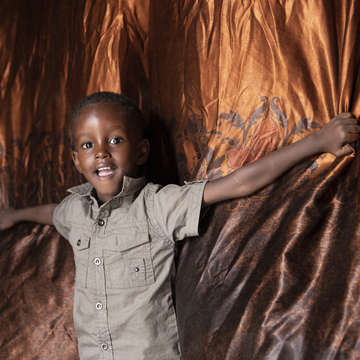 A three-year old boy smiles while standing in his home. In Somalia, where the boy lives, Save the Children is working to protect children and families from the devastating effects of hunger. Photo credit: Kate Stanworth / Save the Children, April 2019. 