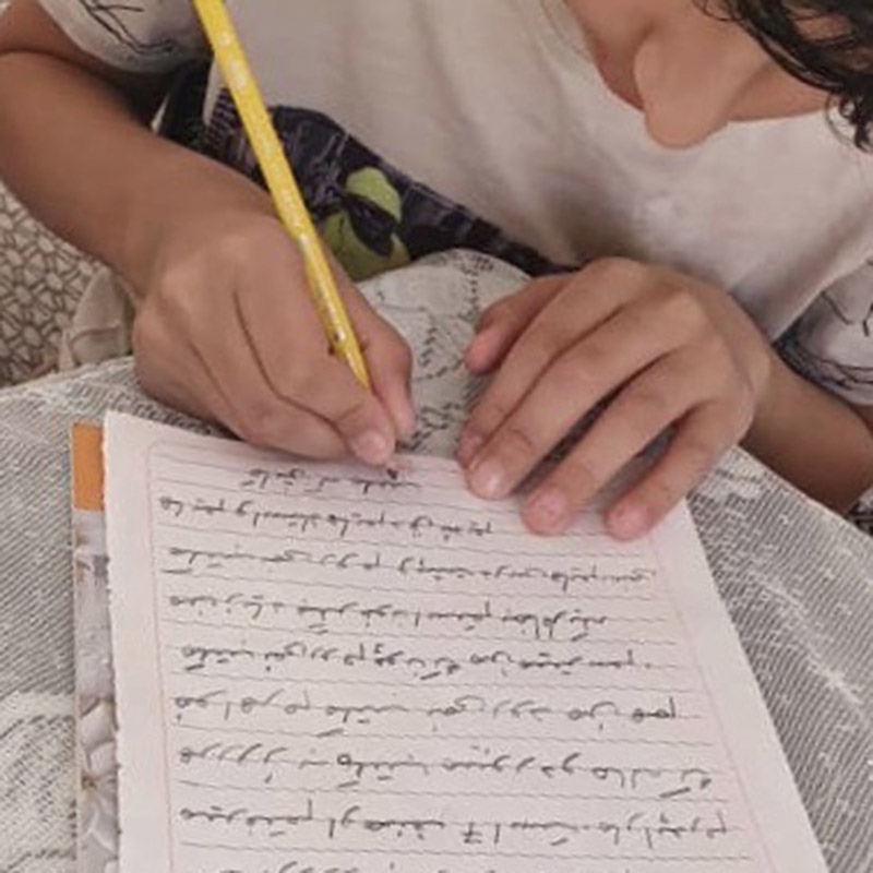 A closeup of an Afghan writing a letter. 
