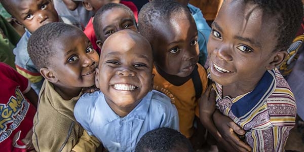 In Malawi, a group of smiling children crowd close together. 