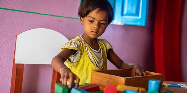 A four-year old girl plays with colorful blocks in a classroom in Nepal. 