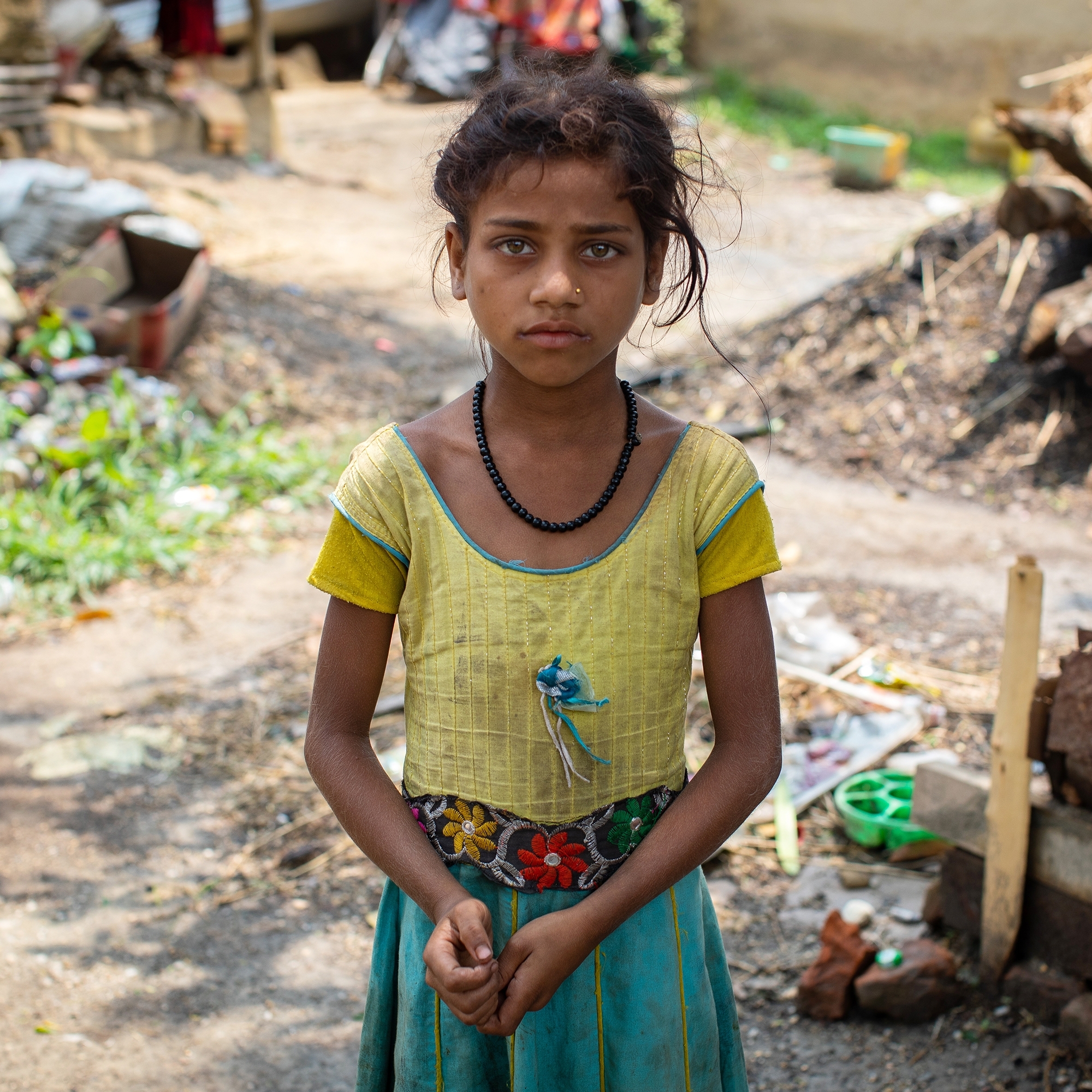 In Nepal, a girl stands outside in a rural farm landscape.