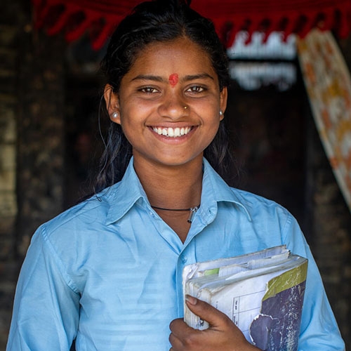 16-year-old Sonu holds onto her school textbook inside of her home in the Kapilvastu region of Nepal.