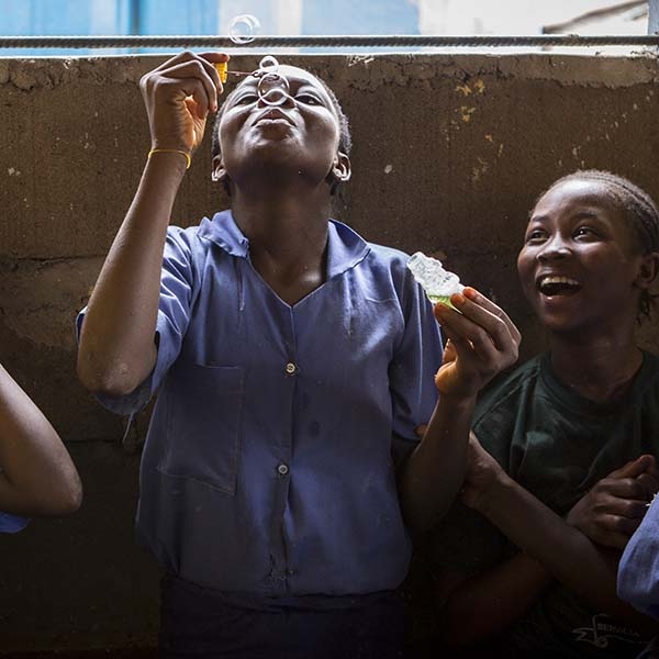 Girls in blue school uniforms enjoy blowing bubbles during a break at school.