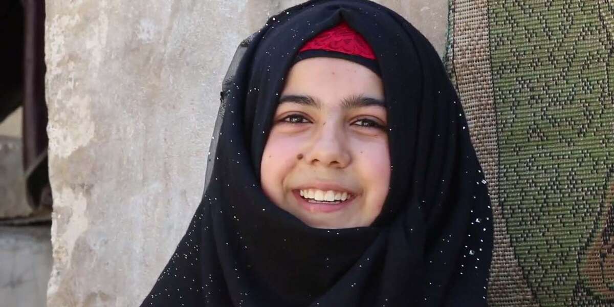 A girl laughs while in her home in Syria where she is able to attend school remotely due to COVID-19.