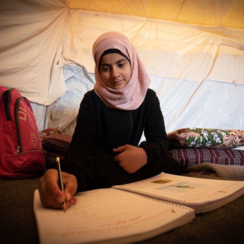 A girl does her homework in a refugee camp in north east Syria