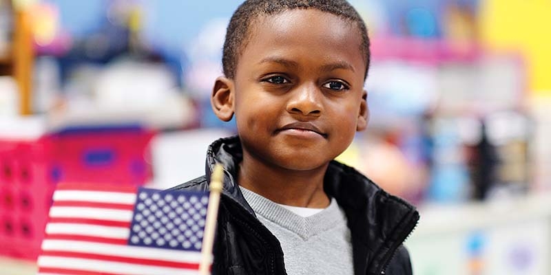 Tennessee, USA, a little boy in a black jacket holds an American flag