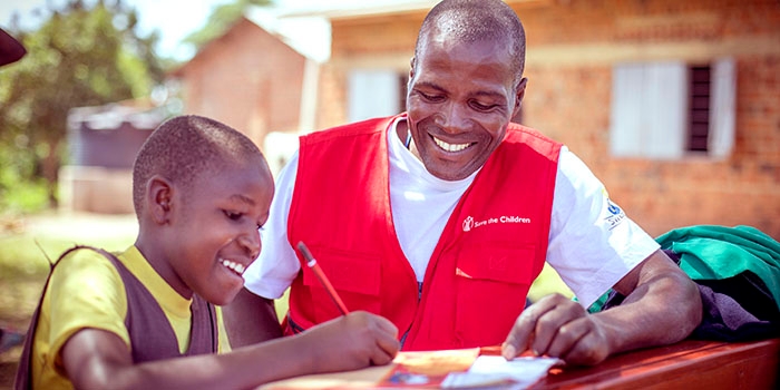 Fred, a Save the Children staff member, guides Dorothy on how to write a letter.