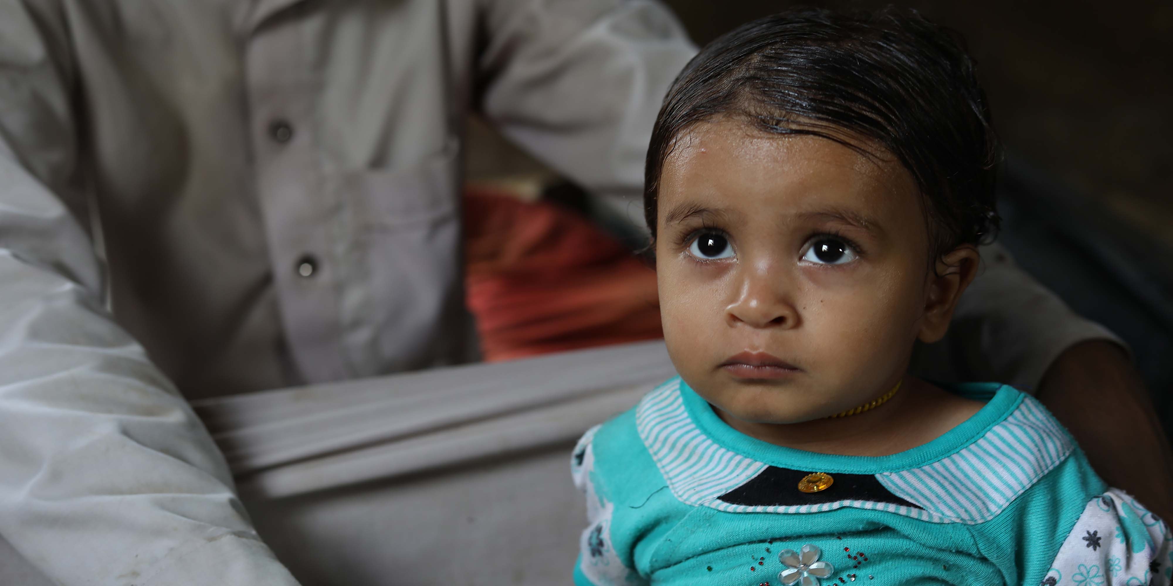 A young girl sits near her father in Yemen after receiving treatment for malnutrition.