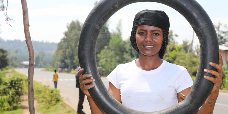 A students in through Save the Children's Young Women's Leadership & Economic Empowerment Program (LEEP) in Ethiopia. holds a tire. 