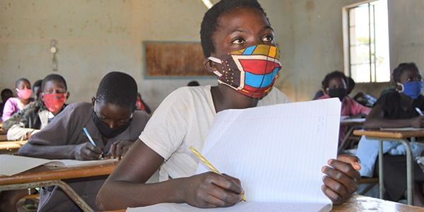 A girl wearing a face mask takes an exam in her classroom in Zambia where schools have reopened since being closed since March due to COVID-19.