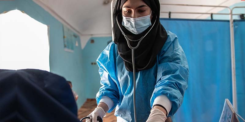 In Afghanistan, female health worker examines a patient in a health center.