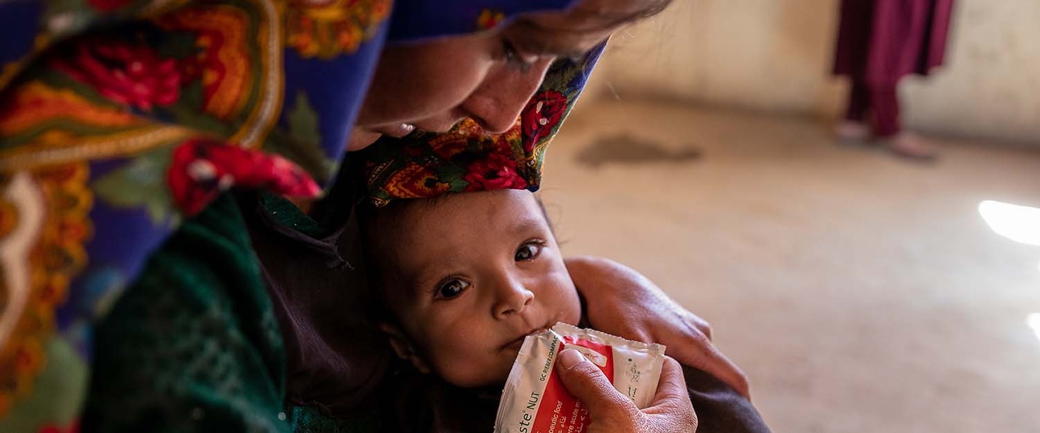 In Afghanistan, a  mother feeds her daughter with therapeutic food used to treat severe acute malnutrition