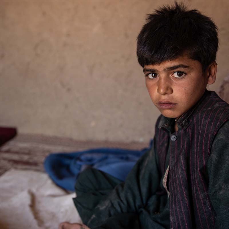 A young afghan boy sits in a shelter. 