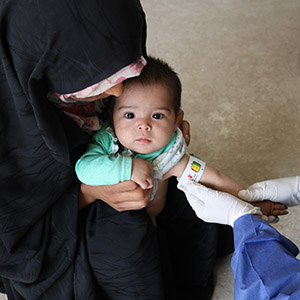A health worker in Afghanistan uses a MUAC band to measure a baby's arm circumference during a screening for malnutrition. 
