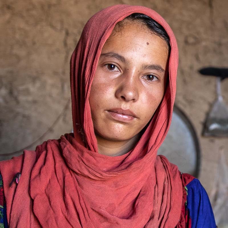 In Afghanistan, a girl stands on her own while looking pensive. 