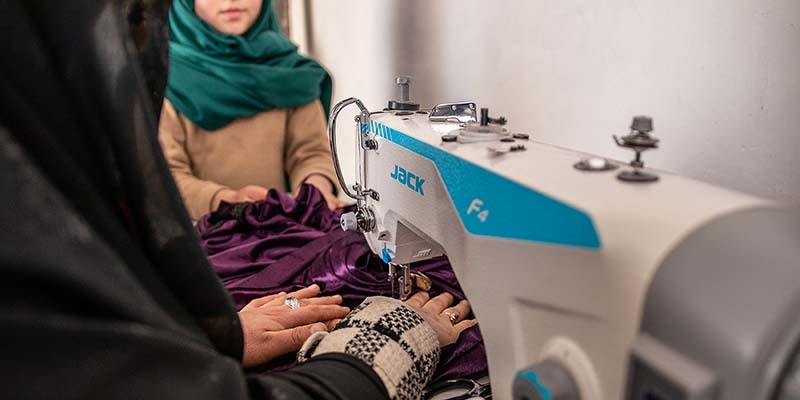 In Afghanistan, a woman and her daughter work together at a sewing machine. 