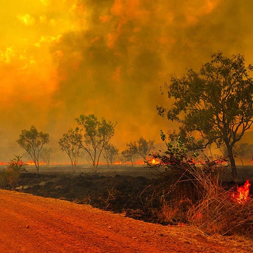 An empty dirt road reflects the red blaze of the enormous and unprecedented Australian bush fires. Smoke and flames appear in the distance, while parts of the horizon are actively burning. Save the Children is helping children and families in Australia who have been impacted by the fires. Photo credit: John Crux Photography.