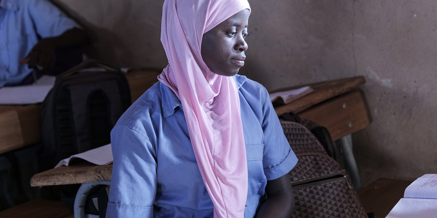 Burkina Faso, a teenage girl in a pink hijab sits in a classroom