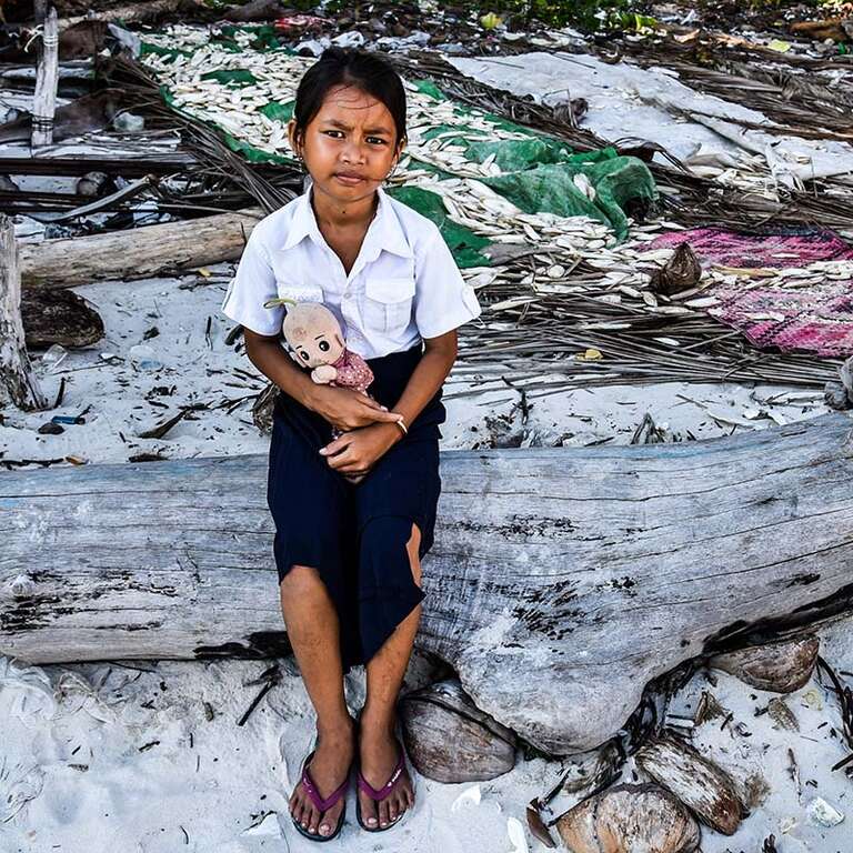 In Cambodia, a young girl stands near the shoreline where debris has washed up. 