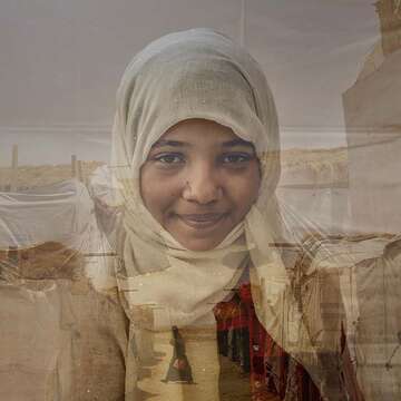 A young girl smiles shyly while standing in front of a landscape in Yemen. 