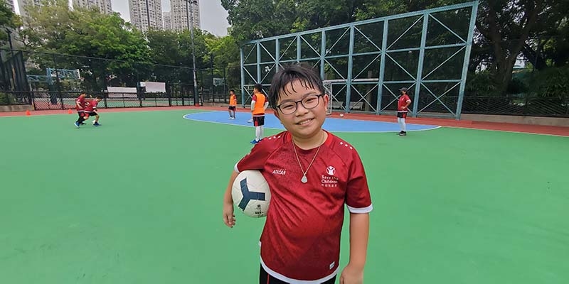 A boy holds a soccer ball while participating in the 'Play to Thrive' program by Save the Children in Hong Kong.