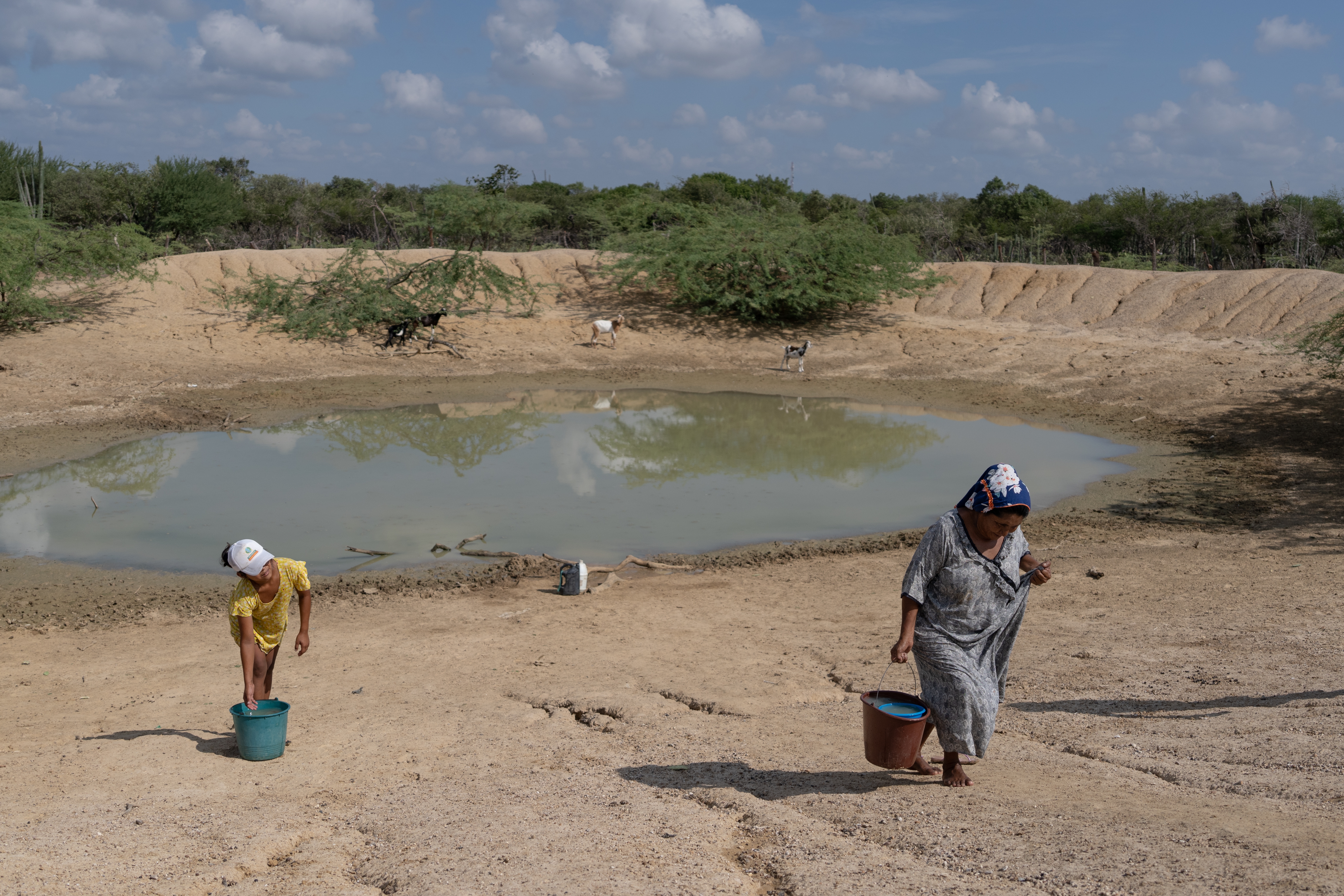 Colombia, a mother and daughter carry water from the "jaguey" for their home in La Guajira.