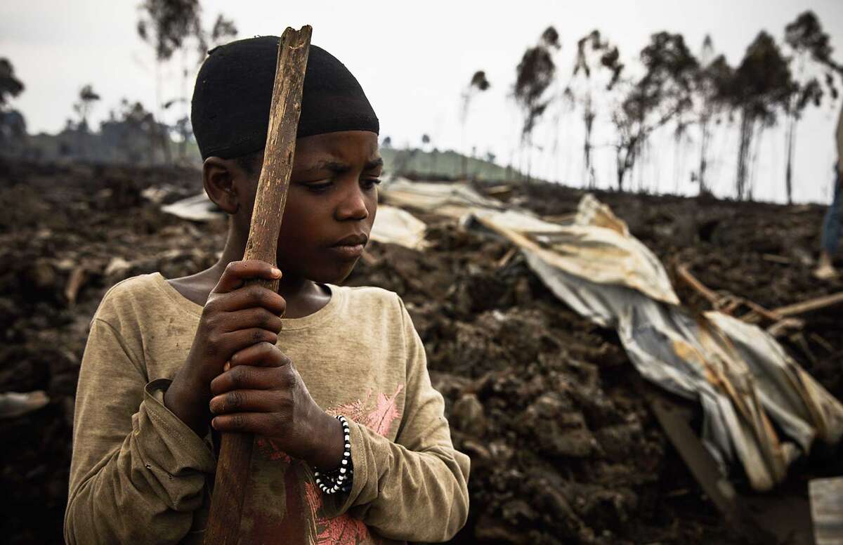 A child stands amongst rubble after fleeing a fire caused by a volcano. 