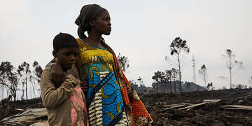 A woman and child stand in the middle of devastation caused by a volcanic explosion in the DRC. 