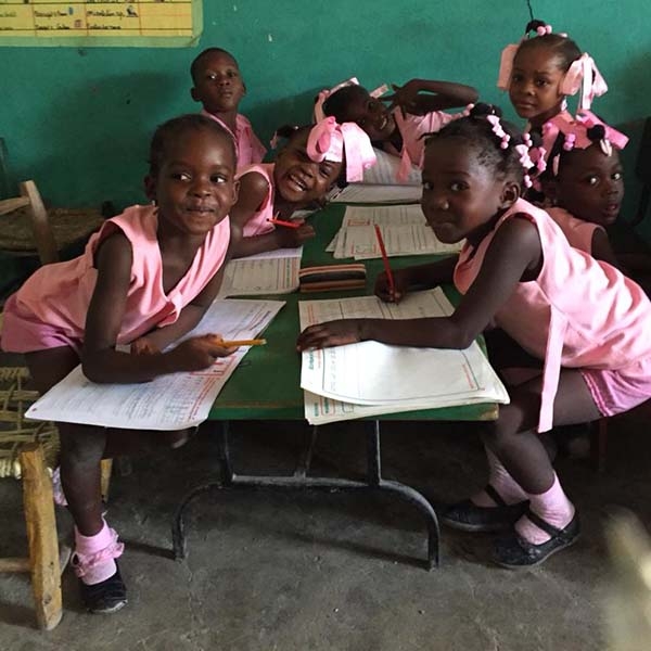 Young schoolchildren in Haiti, dressed in pink uniforms, are busy with their lessons. 