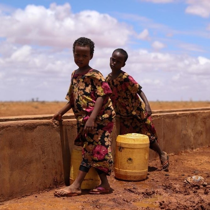 Horn of Africa, two young kids stand with a water jug