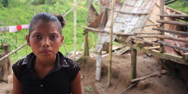 In Nicaragua, a girl stands outside of her home after it was destroyed by a violent storm. 