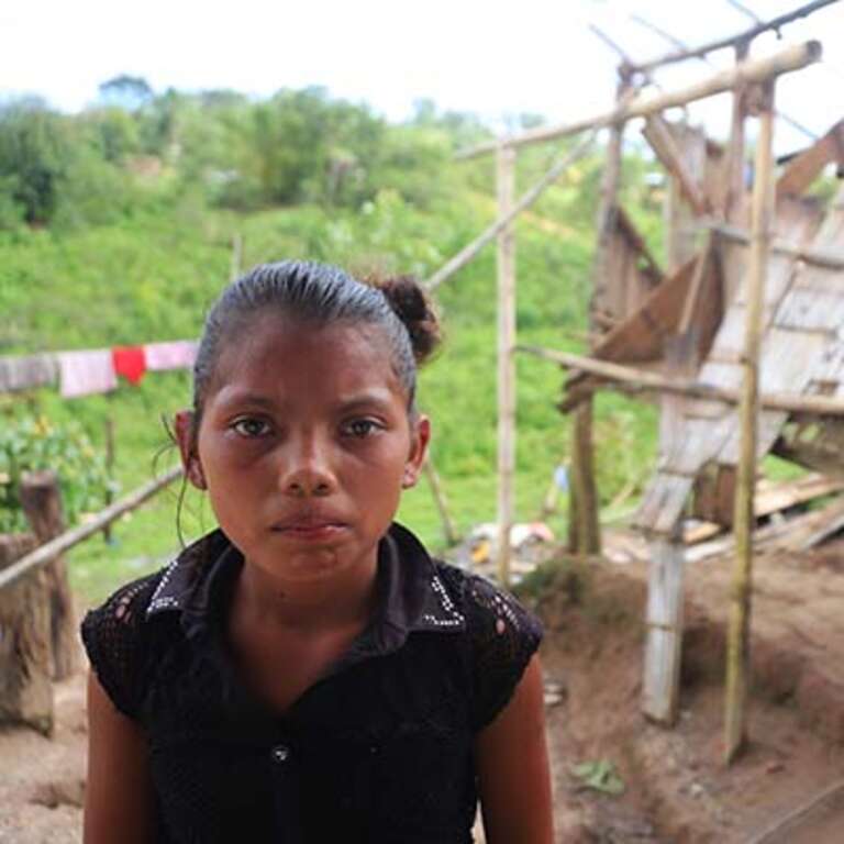 A young girl stands in front of a damaged shelter in Nicaragua following Hurricane Iota.
