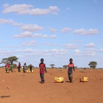 In Kenya, two boys walk across a dusty and drought-ravaged field.
