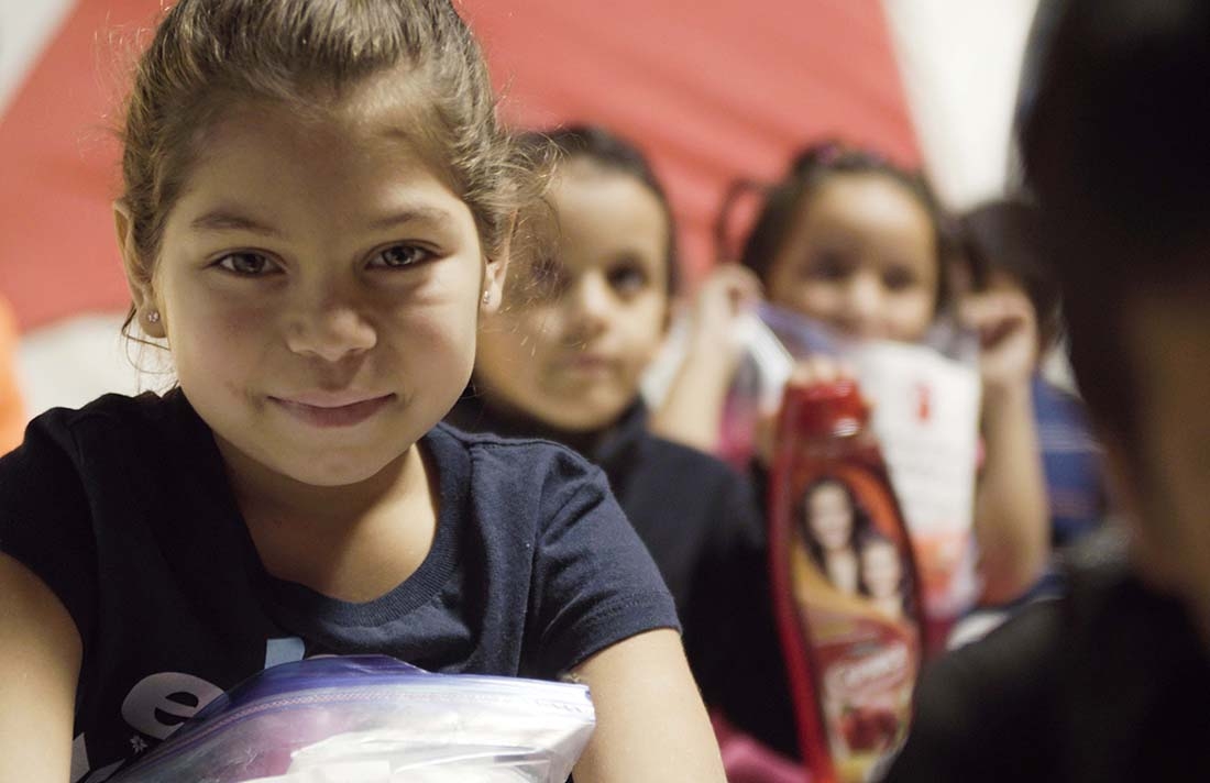 A girl holds a bag of hygiene supplies provided by Save the Children in Mexico.