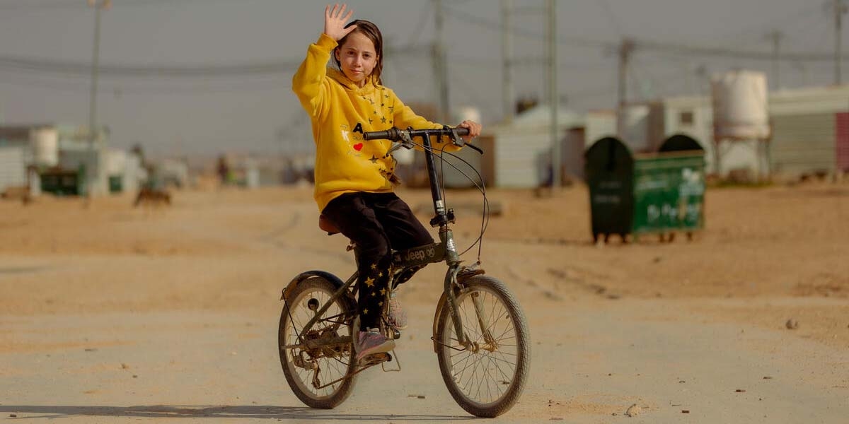 A little girl, sits on a bicycle in a yellow hoodie