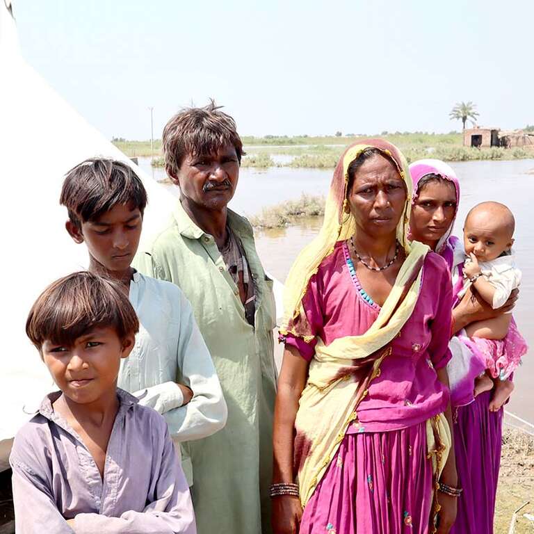 In Pakistan, a family stands near a makeshift shelter after deadly flooding displaced millions. 