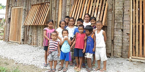 A group of young children stand outside their newly opened Child-Friendly Space constructed by Save the Children in a small mountain village near where Typhoon Haiyan made landfall in 2013. Child-Friendly Spaces provide a safe place for children to play and learn as their communities recover from the devastating effects of natural disasters. Photo credit: Save the Children