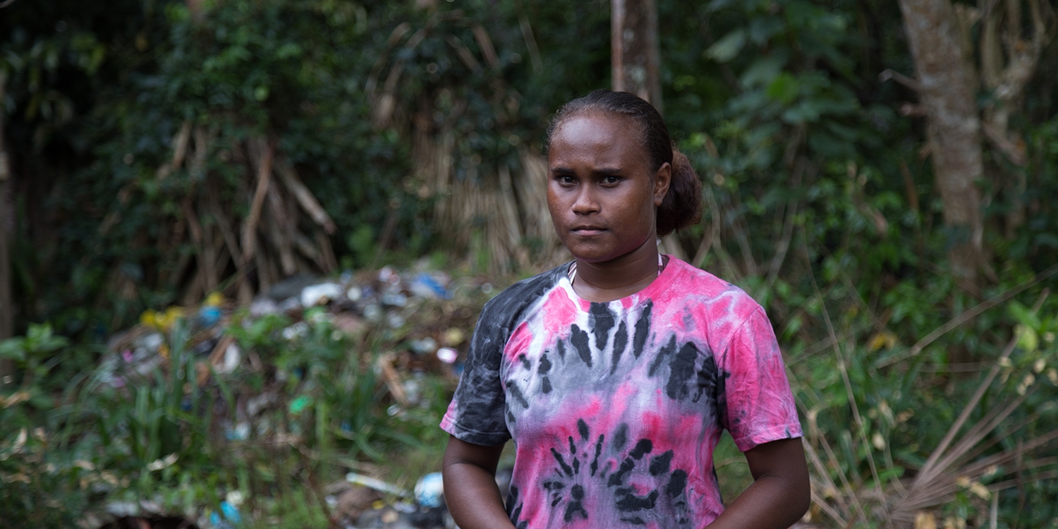 Solomon Islands, a girl in a pink shirt shows the remaining debris following high sea levels near her home.