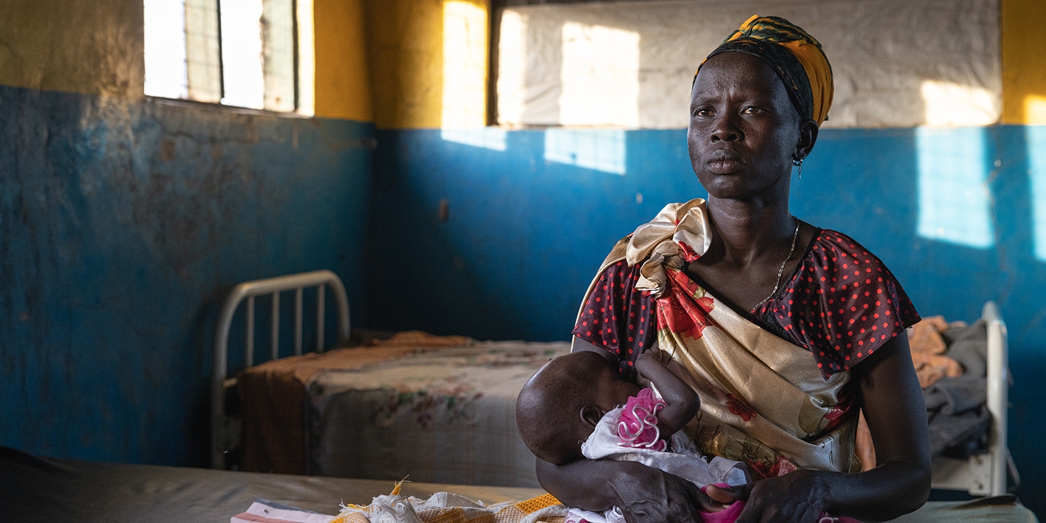 South Sudan. a mother holds her baby in a Save the Children stabilization center