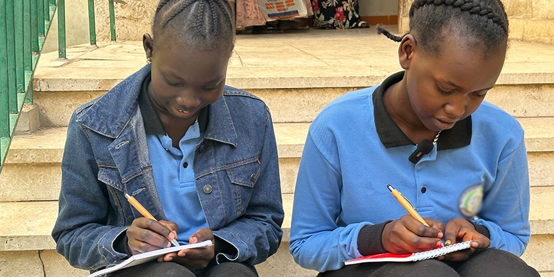 Sudan, two young girls sit together and write.