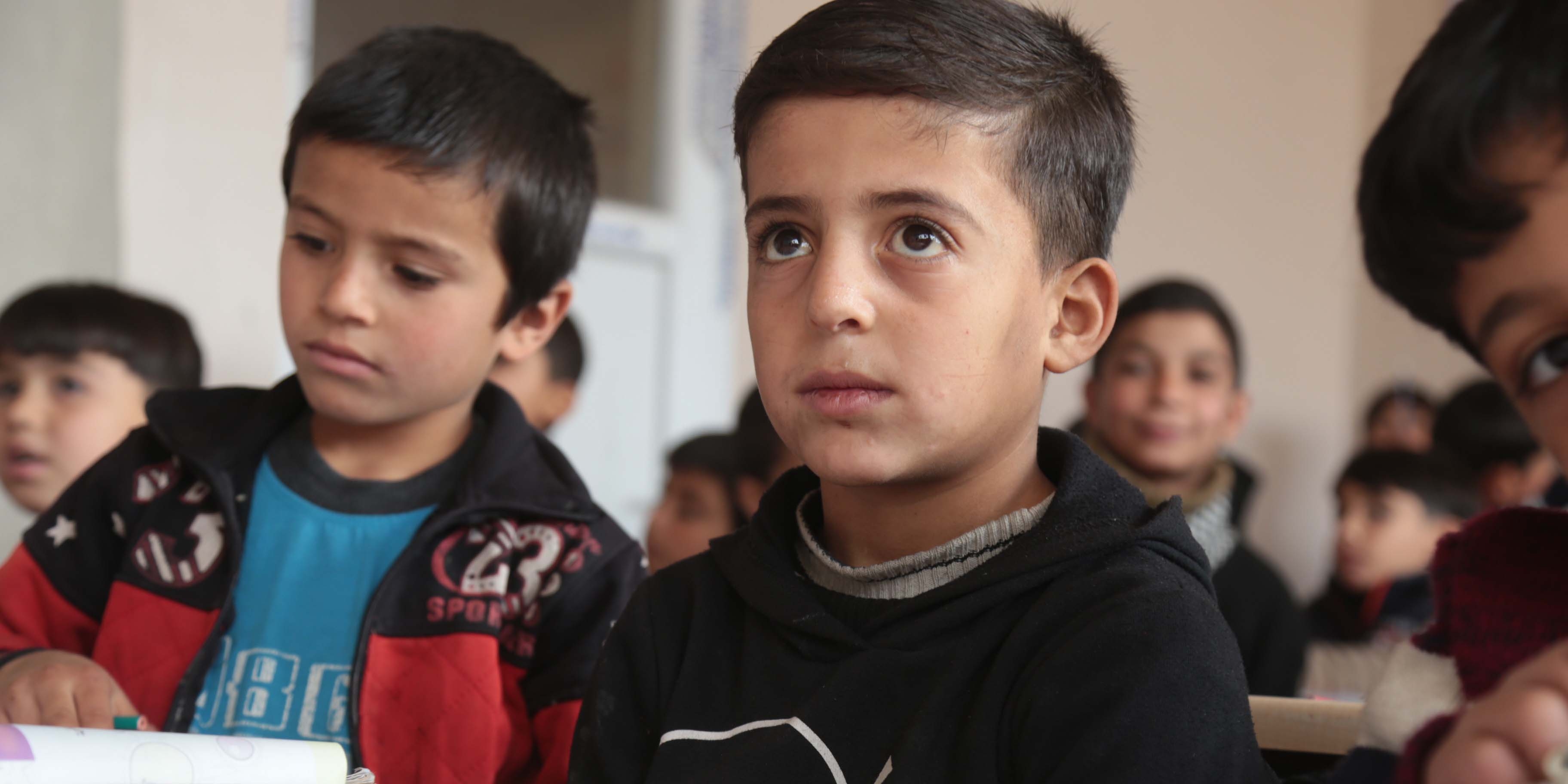 North Syria, an 8 yr. old boy in a black hoodie sits in a classroom