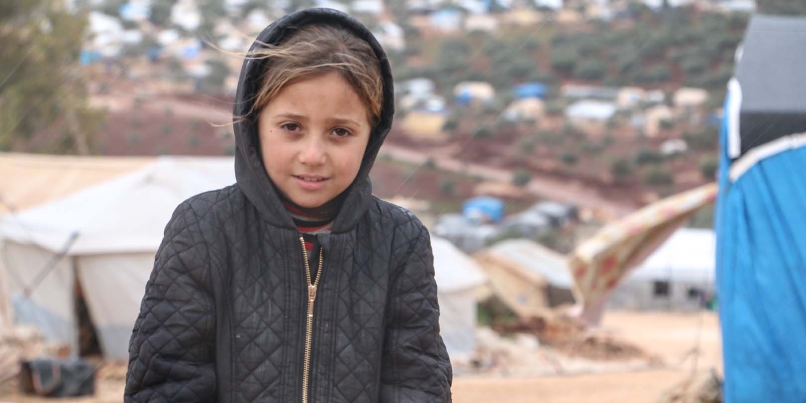 Northwest Syria, a little girl in a black winter coat, lives in a displacement camp