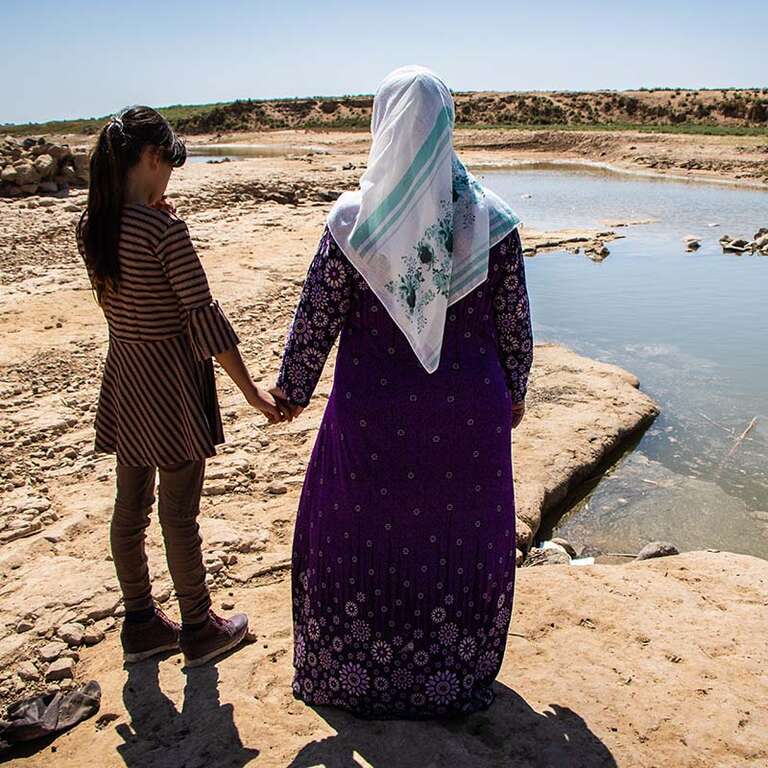 In Syria, a mother and daughter look out over a dried-up lake that has suffered due to the climate crisis.