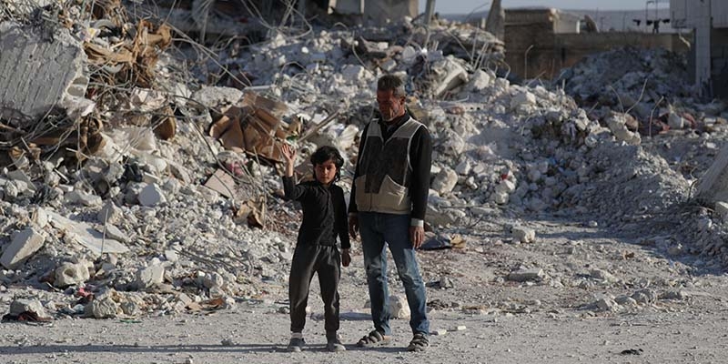 A father and son walk amid the rubble of what was once the neighbourhood where they lived before it was destroyed by the earthquake that hit Syria in February 2023.